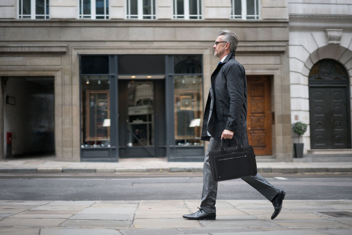 A man walking along a city street carrying the black Alto