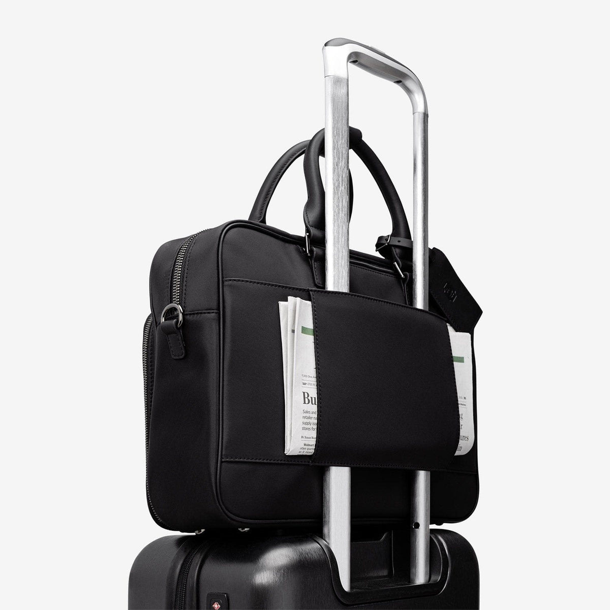 The black Alto mounted on a rolling suitcase by its trolley sleeve