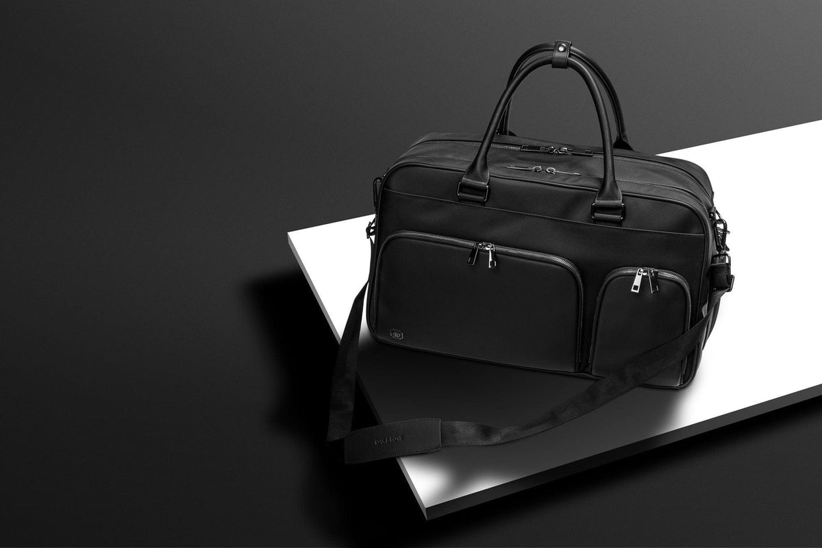 The Kennedy Weekender on a dark table with travel gear